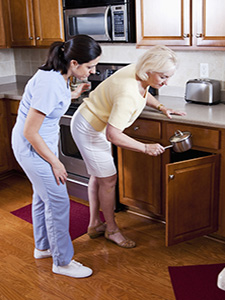 Companion-Homemaker helping senior lady in kitchen